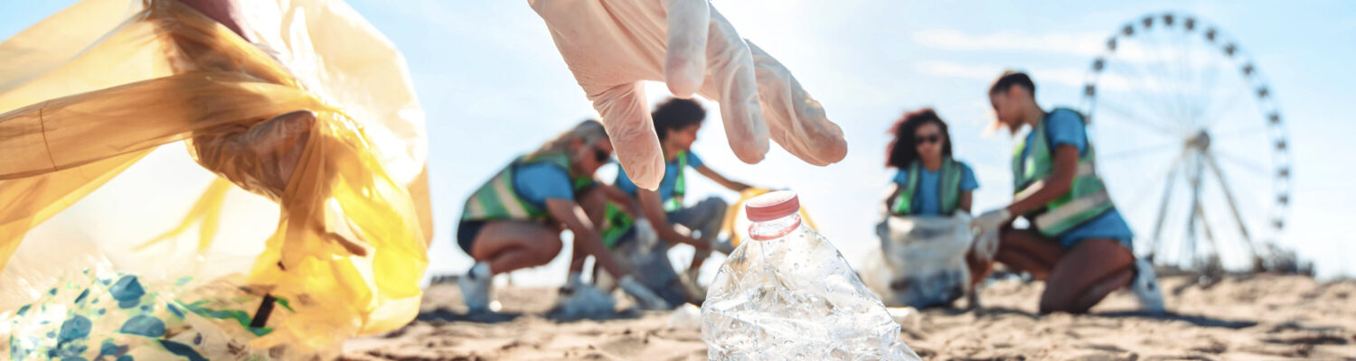 Group of eco volunteers picking up plastic trash on the beach - Activist people collecting garbage protecting the planet - Ocean pollution, environmental conservation and ecology concept