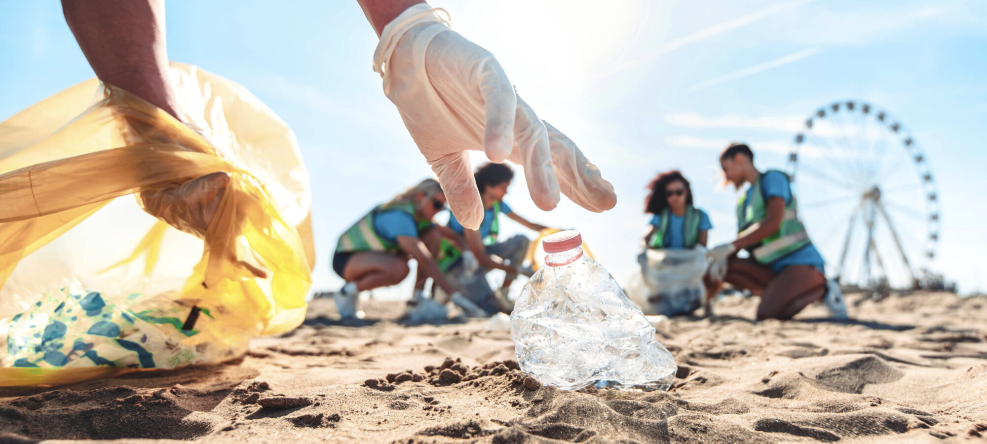 Group of eco volunteers picking up plastic trash on the beach - Activist people collecting garbage protecting the planet - Ocean pollution, environmental conservation and ecology concept