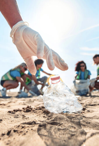 Group of eco volunteers picking up plastic trash on the beach - Activist people collecting garbage protecting the planet - Ocean pollution, environmental conservation and ecology concept